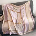 Detailed shot of printed silk shawl with chain motifs and monograms on a soft sofa - 110X110CM / Pink