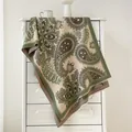 Détail de l'écharpe en cachemire avec motifs paisley et franges sur les meubles - Vert