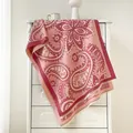 Châle pashmina à motif paisley rose et bordeaux drapé élégamment sur un meuble blanc - Rose