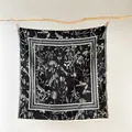 Detalle de bufanda cuadrada vintage con motivos florales y bordes deshilachados - Negro