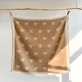 Detail eines weichen kamelfarbenen Schals mit weißen Bienenmustern und Fransenrand - Großes Quadratisches Tuch / Khaki