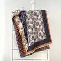 Detail of vintage floral and polka dot scarf with fringes on a white cabinet - Beige Blue