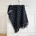 Macro view of thick knitted scarf featuring grey floral motifs and elegant long tassels - Black and Gray