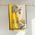 Artistic yellow and beige floral scarf with fringe detail hanging on a wood branch - Yellow