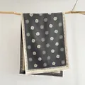 Elegante bufanda de jacquard de camelia gris oscuro con flecos en una rama de madera - Gris
