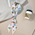 Double-layered silk scarf with colorful handbag print tied elegantly on a light surface - 120x5 / Beige Handbag Print (PD2513-1)