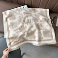 Detail of soft cream shawl with brown floral patterns and fringe on leather sofa - Pear Flower Khaki