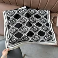 Elegant thick French scarf with black and white floral pattern and fringe edges on sofa - Arranged Flower Black