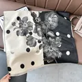 Detail of floral and polka dot cashmere shawl with fringed edges on a leather surface - Color Block Polka Dot Black