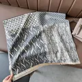Detail of cashmere-like shawl featuring mixed patterns, neutral tones and tassel edges - Patchwork Gray