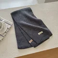 Detail shot of a dark grey wool blend knit scarf with label showing fabric composition - Dark Gray