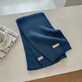 Detail of dark blue wool knit scarf showing fabric label with material composition - Navy Blue