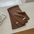 Detailed close-up of dark brown wool blend scarf featuring a premium woven label - Brown