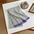 Detail of grey knitted wool scarf with colorful pom poms on a cozy home desk setting - 155x27cm / Gray