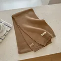 Detailed shot of camel wool blend knit scarf with woven label on soft textured background - Khaki