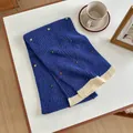 Detail of royal blue knit scarf featuring colorful dot accents and cream contrast hem - 155x27cm / Blue
