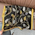 Detail eines schwarzen Kaschmirschals mit goldenem Blatt-Jacquard und Fransen - Blatt Schwarz