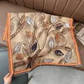 Detail eines khakifarbenen Schals mit Herbstblattmuster und orangefarbenen Fransen - Blatt Erdgelb