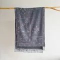 Detail of bohemian paisley jacquard shawl with tassel fringe on a wooden branch - Gray