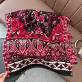 Close-up of red and black paisley shawl with fringe detail on a leather background - Paisley - Black