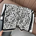 Dettaglio dello scialle jacquard a fiori bianchi e neri con frange sottili sul divano - 180x65cm / Nero