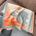 Close-up of floral print pashmina with decorative fringe on a leather surface - 180x65cm / Light Blue Orange