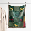 Detail of soft green scarf featuring colored horse patterns and tassel hem on display - Color 5 - Dark Green Multicolor Horse Pattern