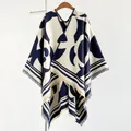 Detail of navy and cream knit poncho featuring cross-stitch trim and long fringed hemline - Blue