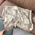 Dettaglio di sciarpa in cashmere con motivo floreale e frange su un divano in pelle - 180x65cm / Cachi