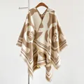 Macro detail of camellia pattern and fringe texture on a thick knit shawl poncho - Khaki