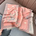 Dettaglio trama sciarpa floreale etnica con nappine su sfondo di pelle - Rosa