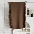 Détail d'une écharpe marron aspect cachemire avec franges et étiquette A.W Studios - Café