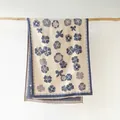 Dettaglio di un'elegante sciarpa con fiori e morbide frange bianche su supporto - Blu