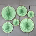 Close-up of 6-piece mint green paper fans with scalloped gold foil edges for party decor - Green with Gold Trim