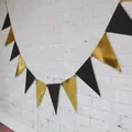 Black and metallic gold triangle bunting banner hanging on a white textured wall - Black Gold Triangle Bunting
