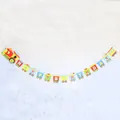 Colorful cartoon train Happy Birthday banner hanging on a white brick wall - Train Theme