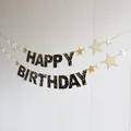 Detail of Happy Birthday banner with black and gold star patterns on a white wood wall - 5
