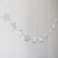 Detail of silver wavy star garland banner hanging on a white striped wall decoration - Silver Stamped Stars