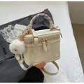 Detail of cream box bag with silk scarf handle and plush pompom charm decoration - Off White