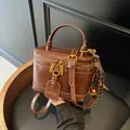 Bolso estilo caja vintage de cuero marrón con detalles dorados y asa superior - Marrón