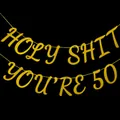 Golden glitter 'Holy Shit You're 50' birthday banner hanging on a black background - Holy Shit You're 50 / Gold