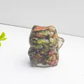 Detail of a lucky cat resin ornament filled with natural colorful crystals on white background - Unakite
