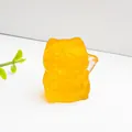 Transparente bernsteinfarbene Winkekatze aus Kunstharz mit Citrin-Kristallen auf weiß - Citrin