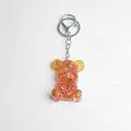 Translucent pink resin bear keychain with gold foil flakes and gear details - Watermelon Crystal Style