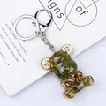 Green moss and golden gears embedded in a transparent resin bear keychain charm - Peridot Style