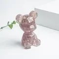 Bärenfigur aus lila Amethyst-Kristallen mit Goldfolien-Akzenten auf weißem Sockel - Erdbeerquarz