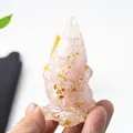 Mano che tiene una statuetta di gnomo in cristallo rosa con scaglie decorative dorate - Quarzo rosa