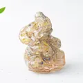 Macro detail of amber resin Ganesha elephant statue with golden hair-like inclusions - Rutilated Quartz
