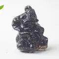 Figura de elefante de obsidiana negra pulida con trompa levantada en piedra blanca - Obsidiana