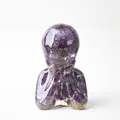Meditating resin figurine with purple amethyst crystal stones on a white background - Amethyst